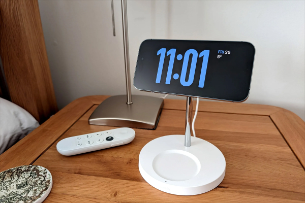 Smartphone with alarm ringing next to an old-fashioned bedside alarm clock.