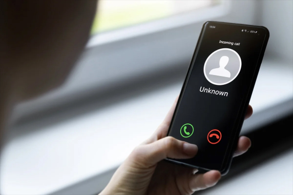 Smartphone displaying a video call, with a dusty landline telephone in the background.