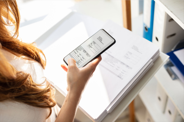 Smartphone scanning a document using a scanning app, while a fax machine appears outdated beside it.