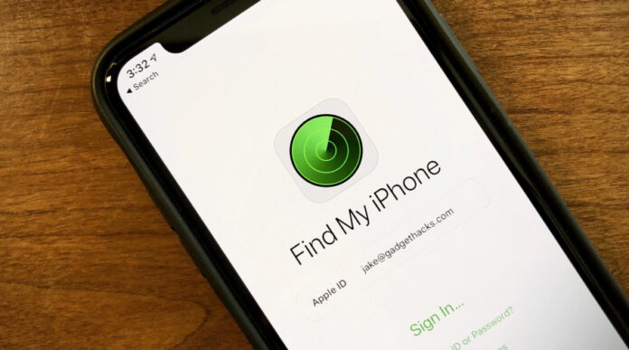iPhone showing the Find My iPhone sign-in screen with the green radar icon on a wooden table.