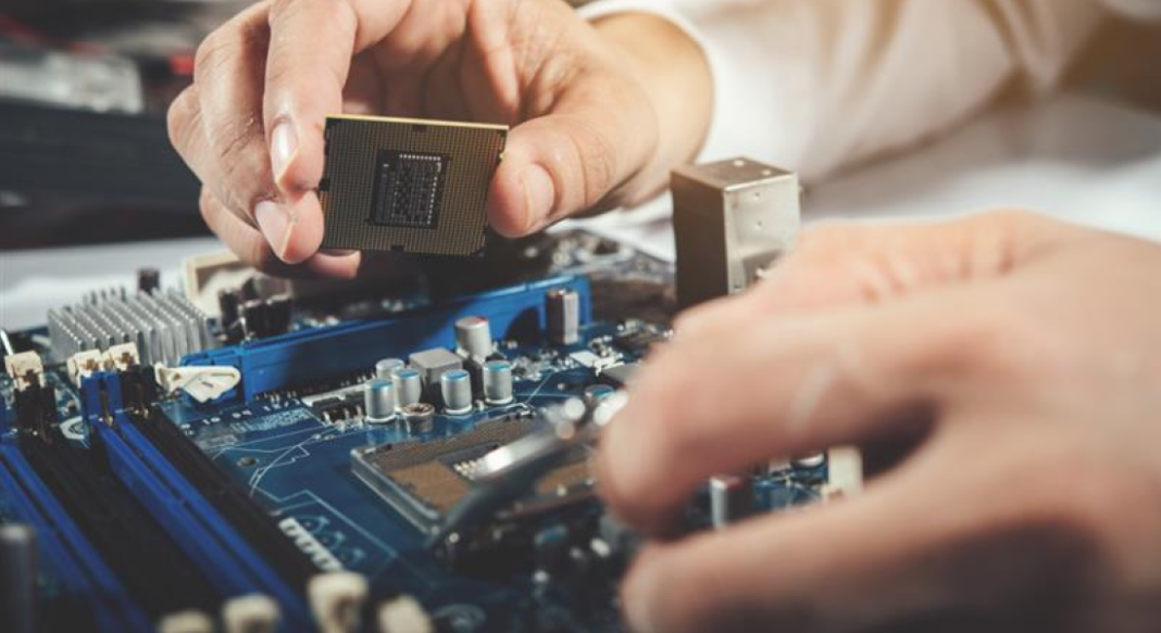 Person installing a CPU onto a blue motherboard during PC assembly, close-up shot on the circuit board image.