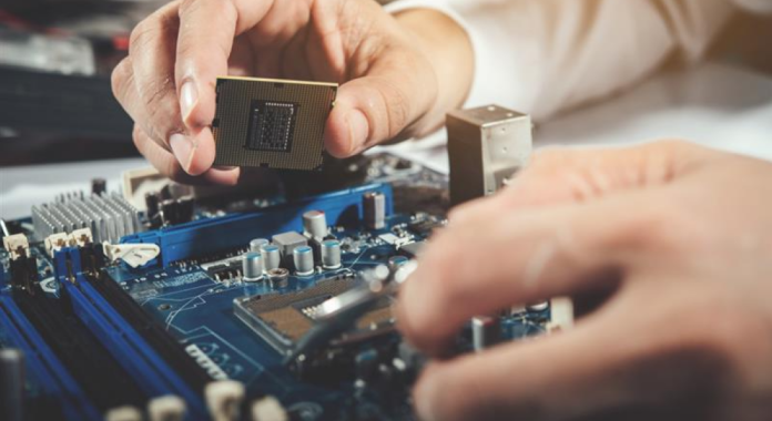 Person installing a CPU onto a blue motherboard during PC assembly, close-up shot on the circuit board image.